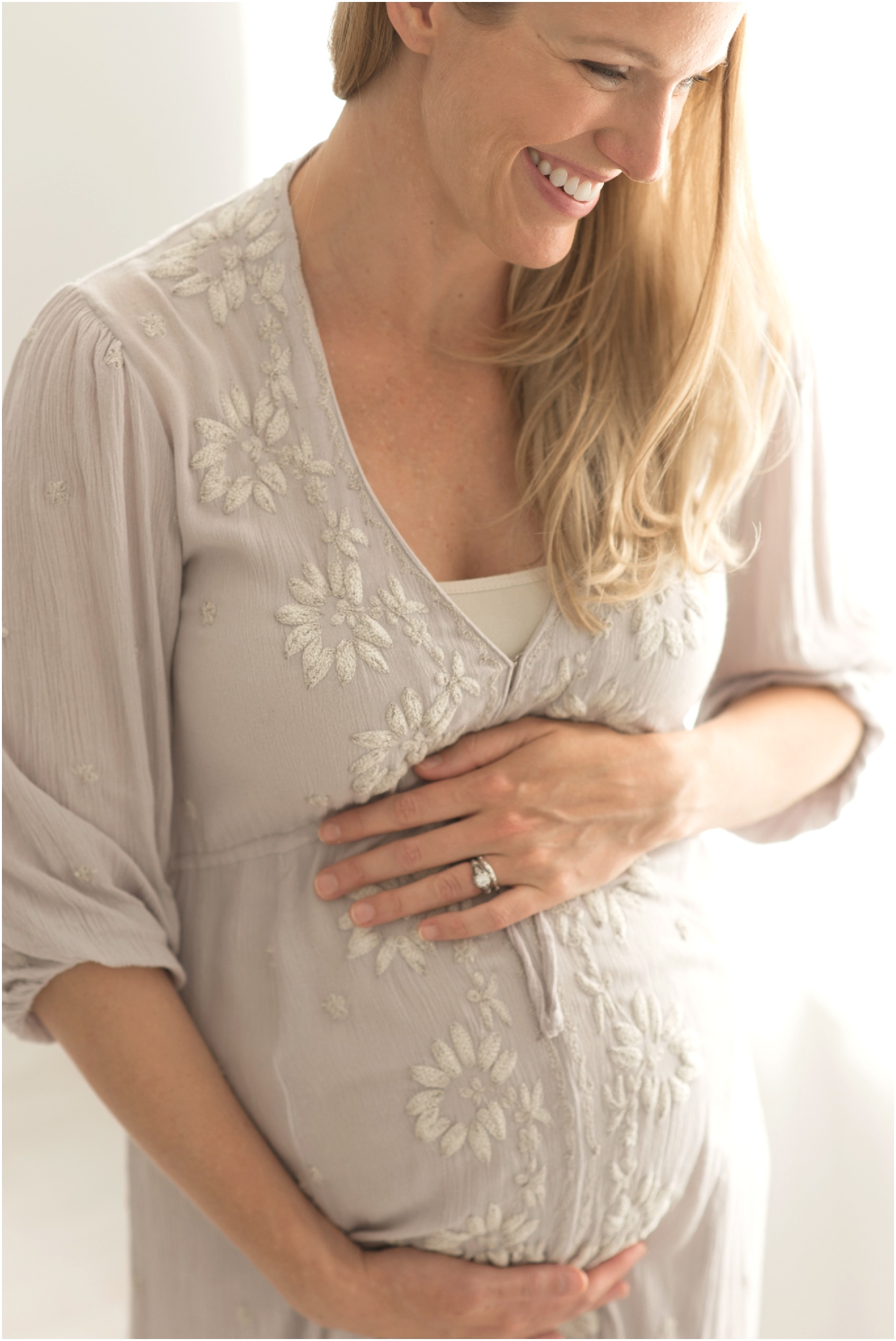 Woman holding stomach in maternity photo.