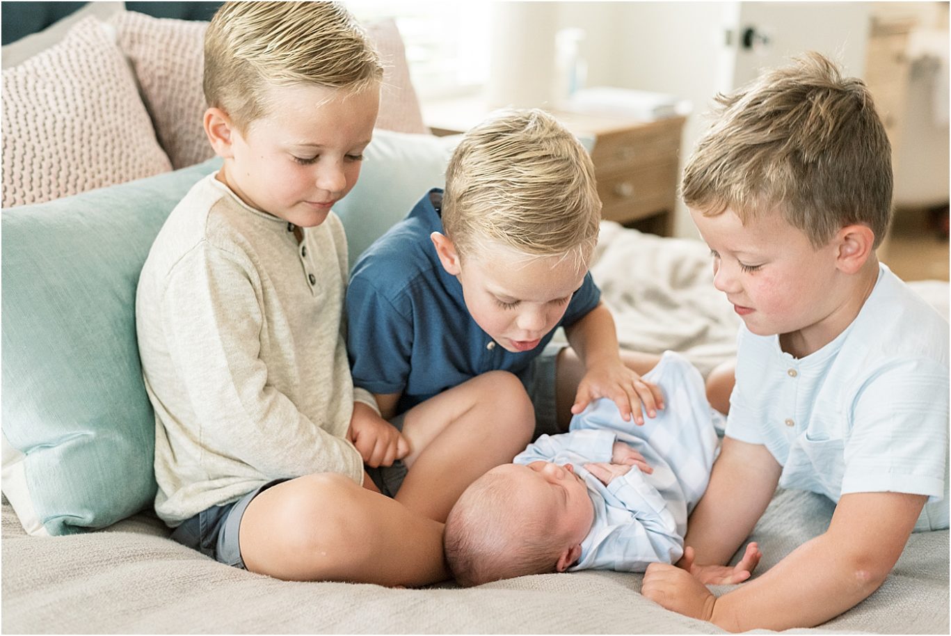 Three big brothers looking at their new baby brother. Photo by Lindsay Konopa Photography.
