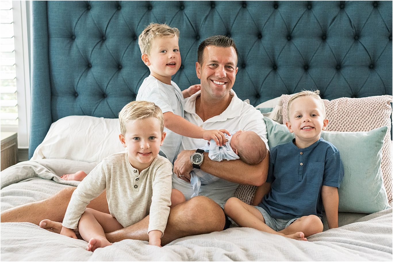 Dad and his four boys sitting together on bed. Photo by Lindsay Konopa Photography.