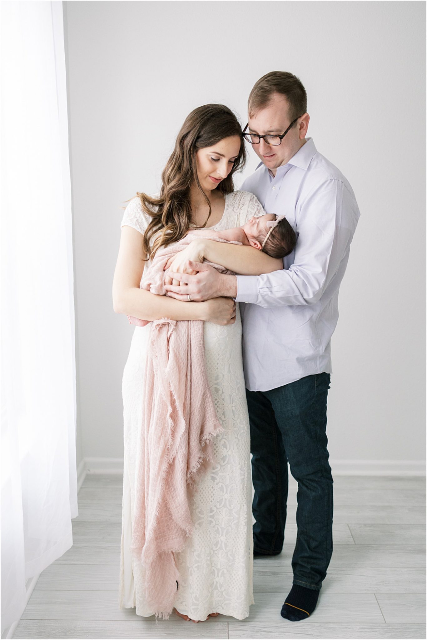 Mom and Dad adoring their brand new baby girl during her newborn photoshoot in a photography studio in Fishers Indiana. Photo by Lindsay Konopa Photography.