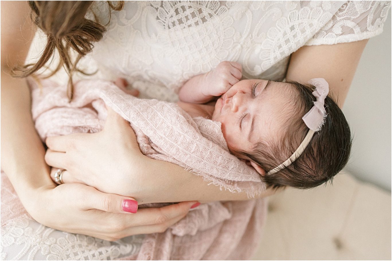 Baby girl swaddled in soft blush pink in Mom's arms. Photo by Lindsay Konopa Photography.