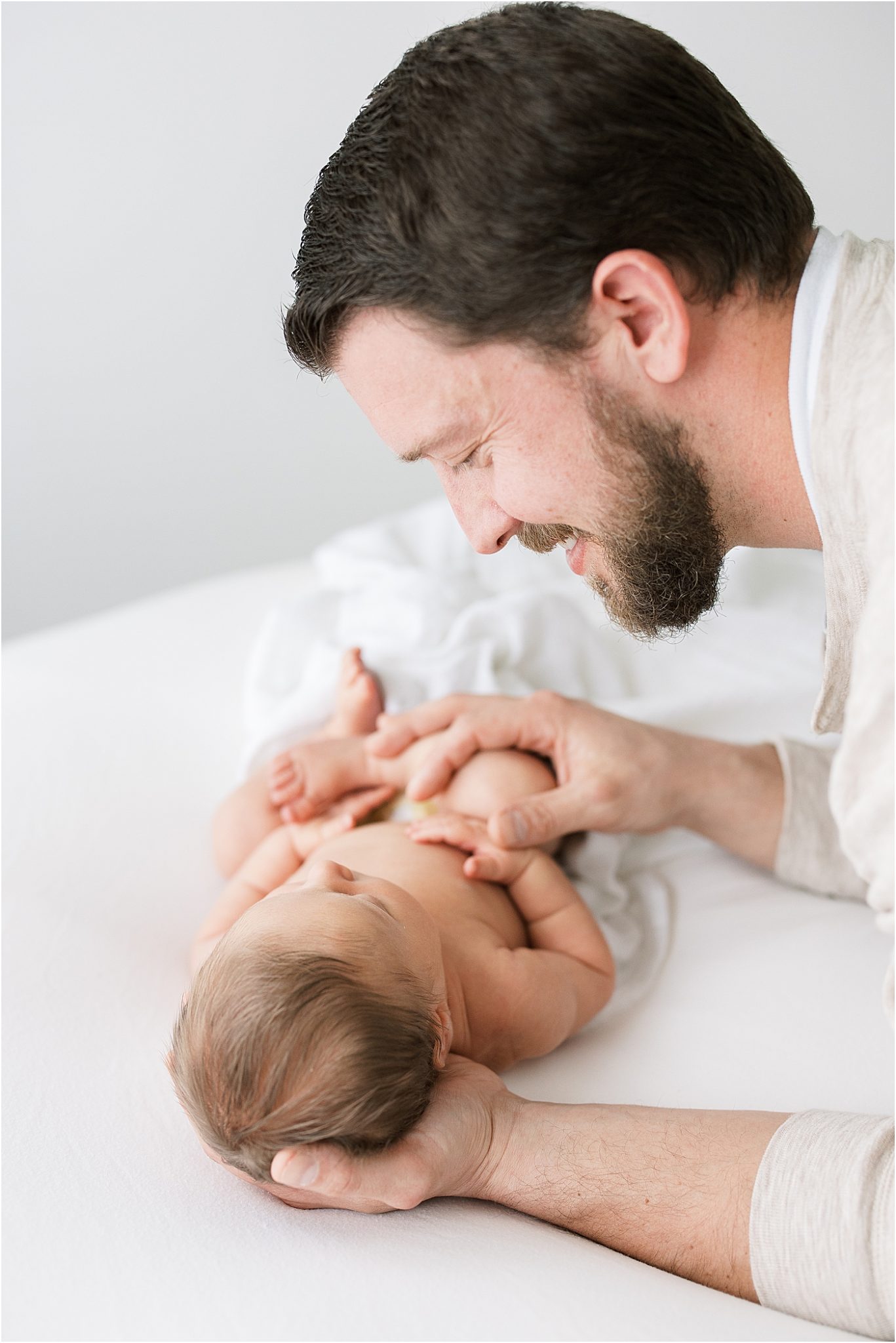 Dad looking down at his son during newborn session. Photo by Bloomington Newborn Photographer, Lindsay Konopa Photography.
