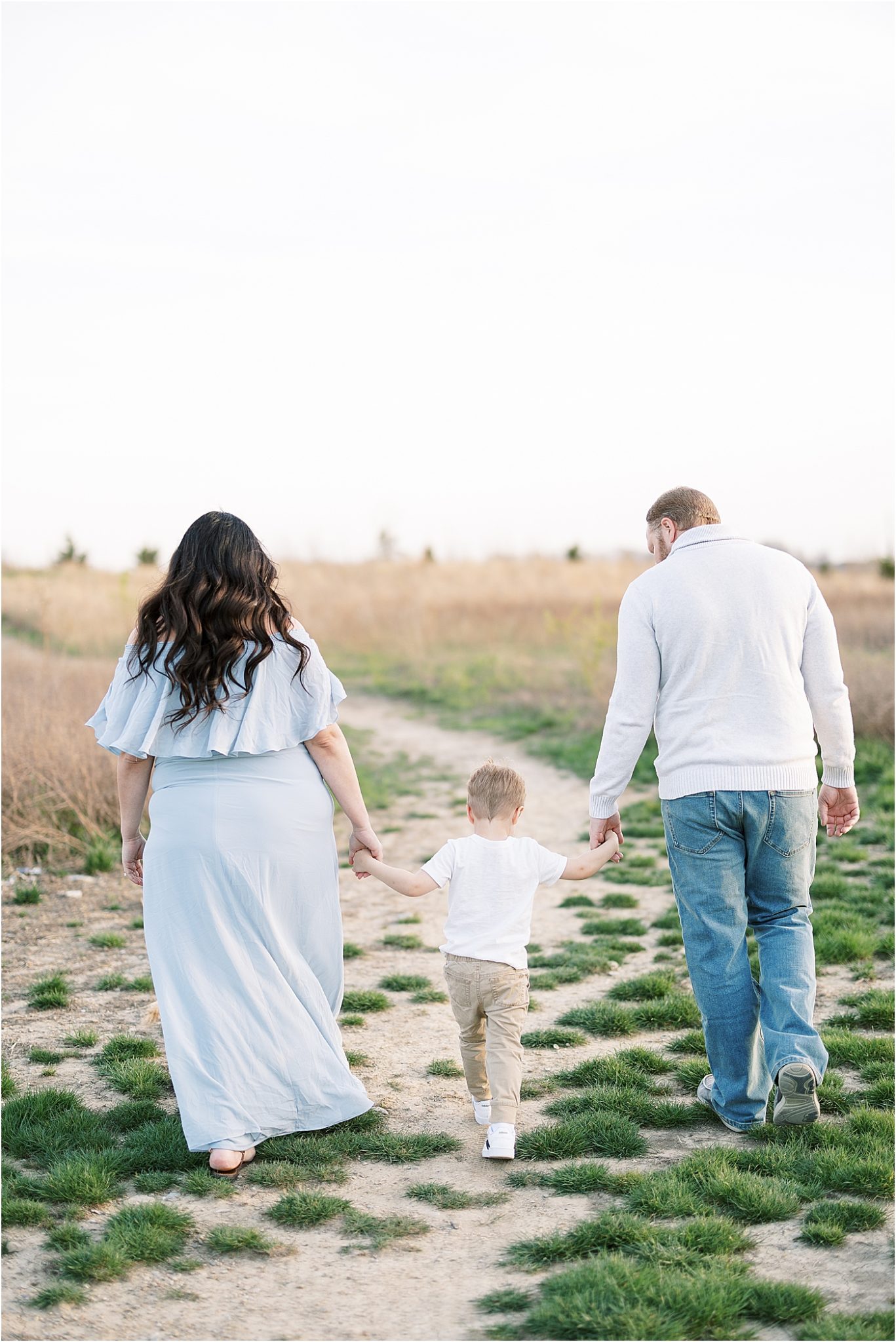Mom and Dad walking with son through field in Fishers | Lindsay Konopa Photography