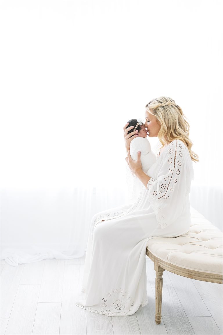 Mom sitting on bench holding baby girl. Newborn photos by Fishers Newborn Photographer, Lindsay Konopa Photography.