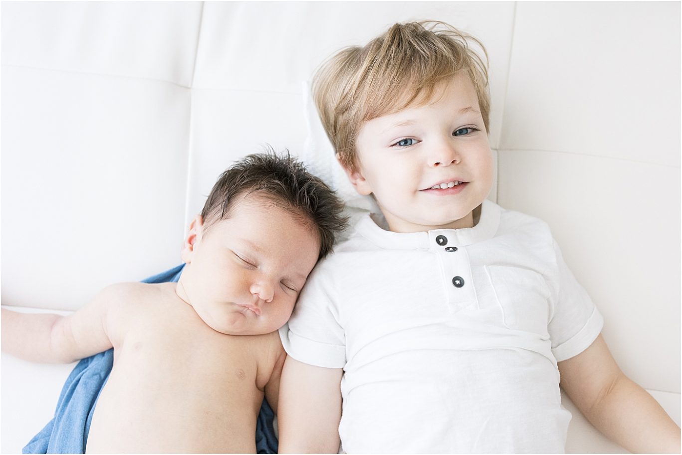 Baby brother and big brother laying side by side. Photo by Lindsay Konopa Photography.