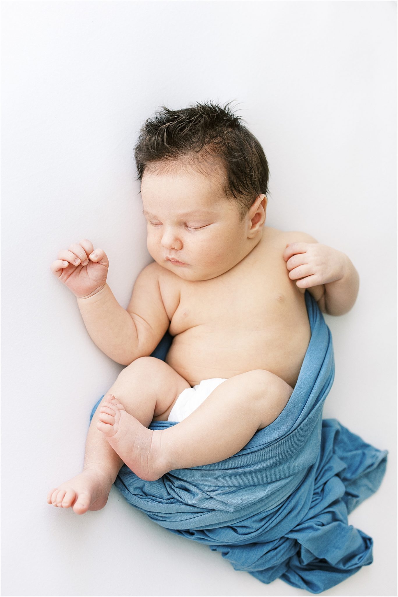 Baby boy swaddled in blue. Photo by Lindsay Konopa Photography.