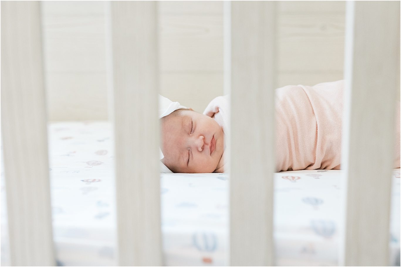 Baby girl laying in her crib. Photo by Lindsay Konopa Photography.