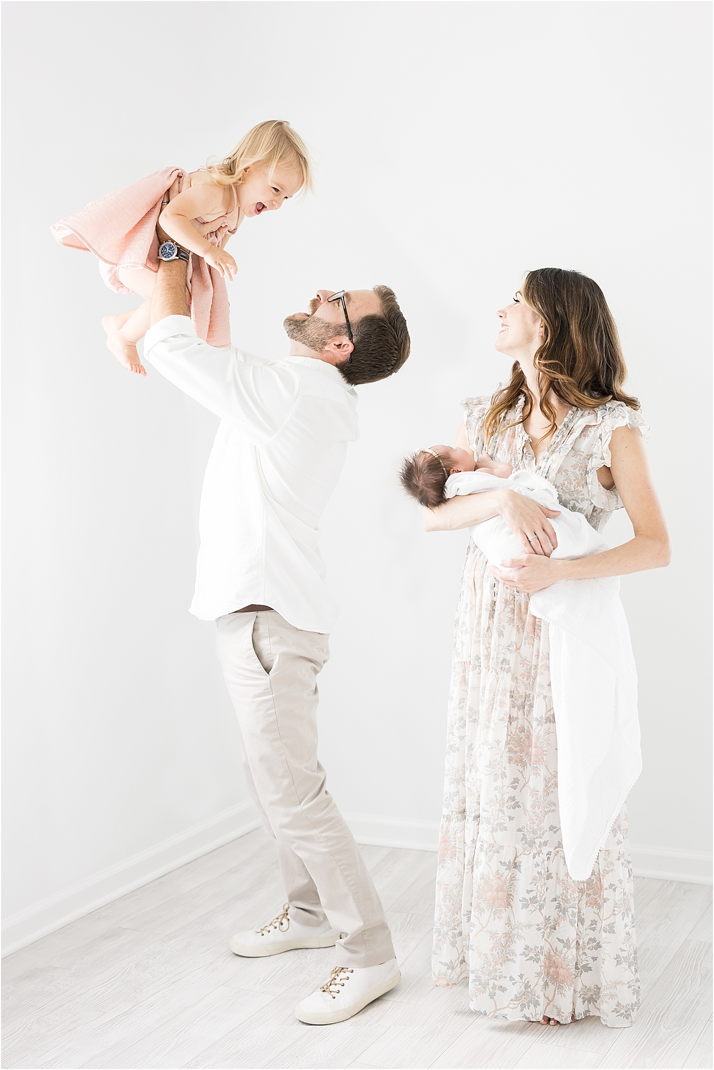 Newborn session in studio in Fishers- Dad playing airplane with toddler and mom holding baby. Photo by Lindsay Konopa Photography.