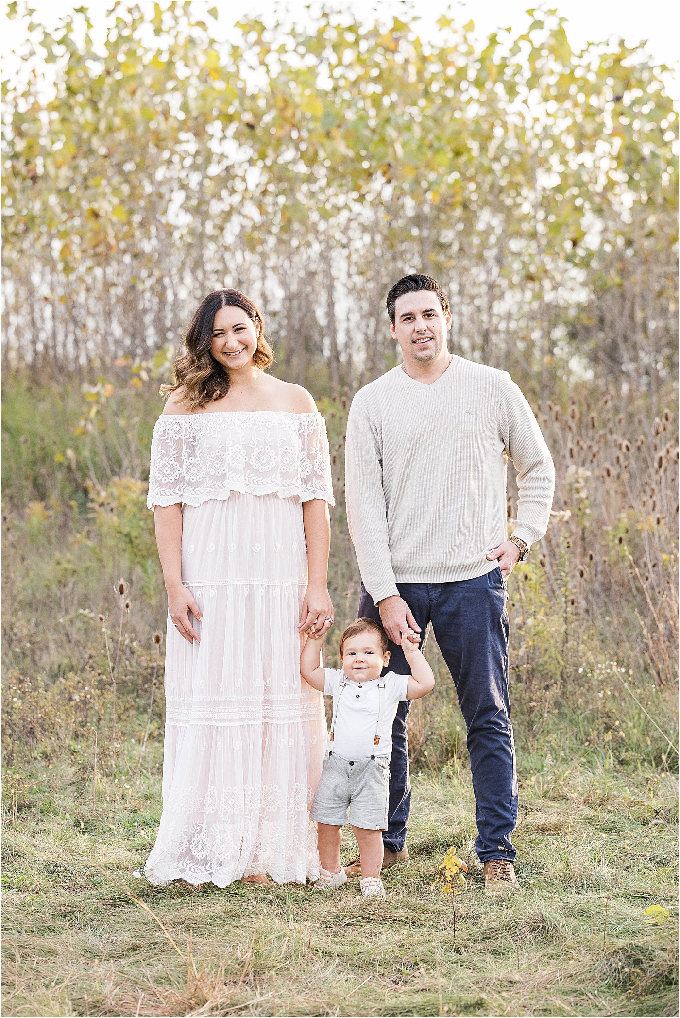 mom and dad stand with toddler boy in Geist, Indiana for sunset photo session