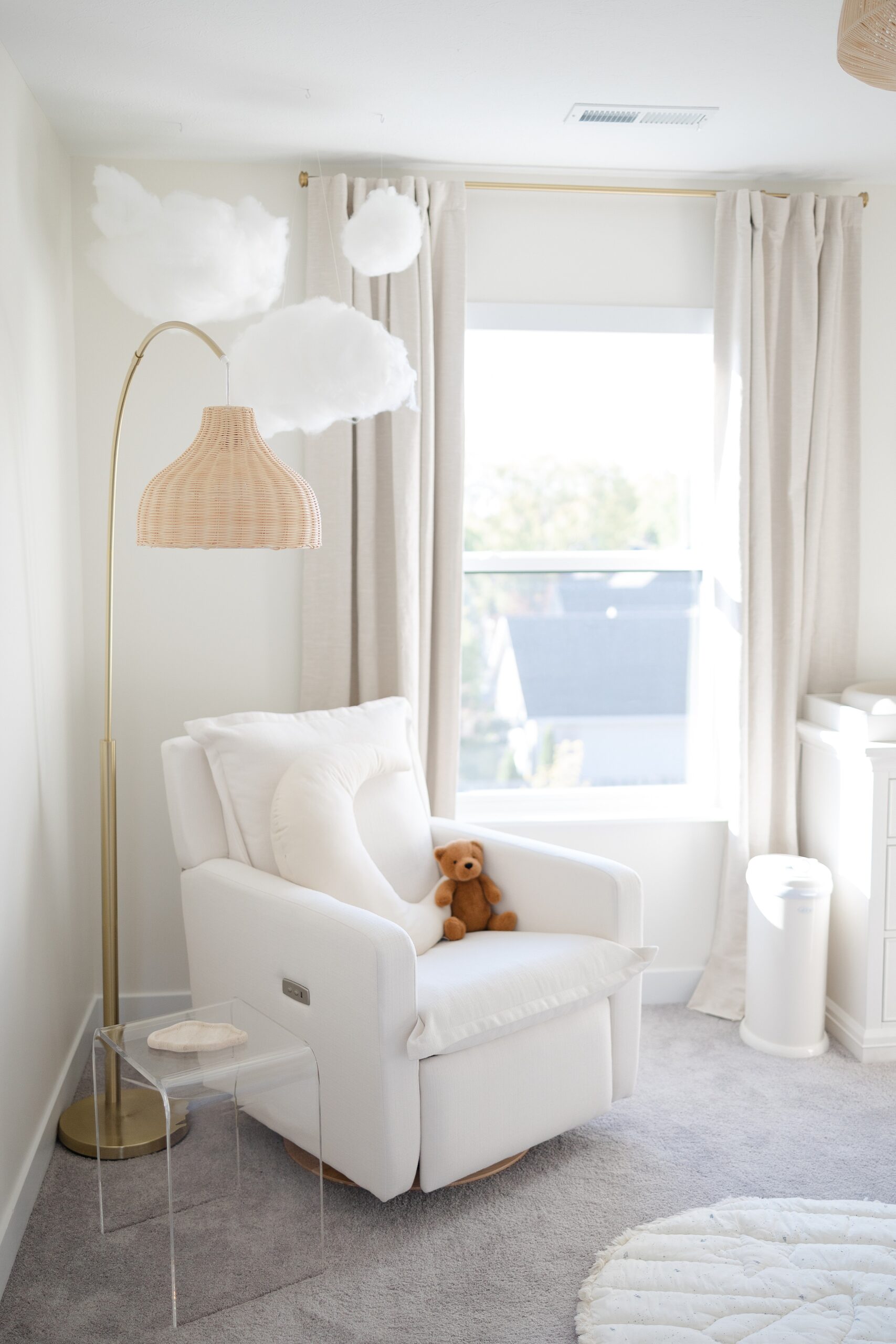 A view of a modern styled nursery with white chair and grey carpet